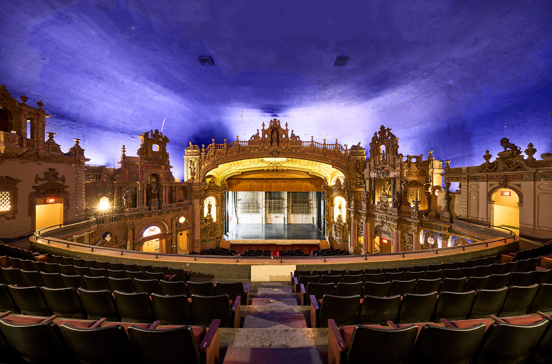 Rows of seats frame the stage beneath the sweeping blue ceiling.