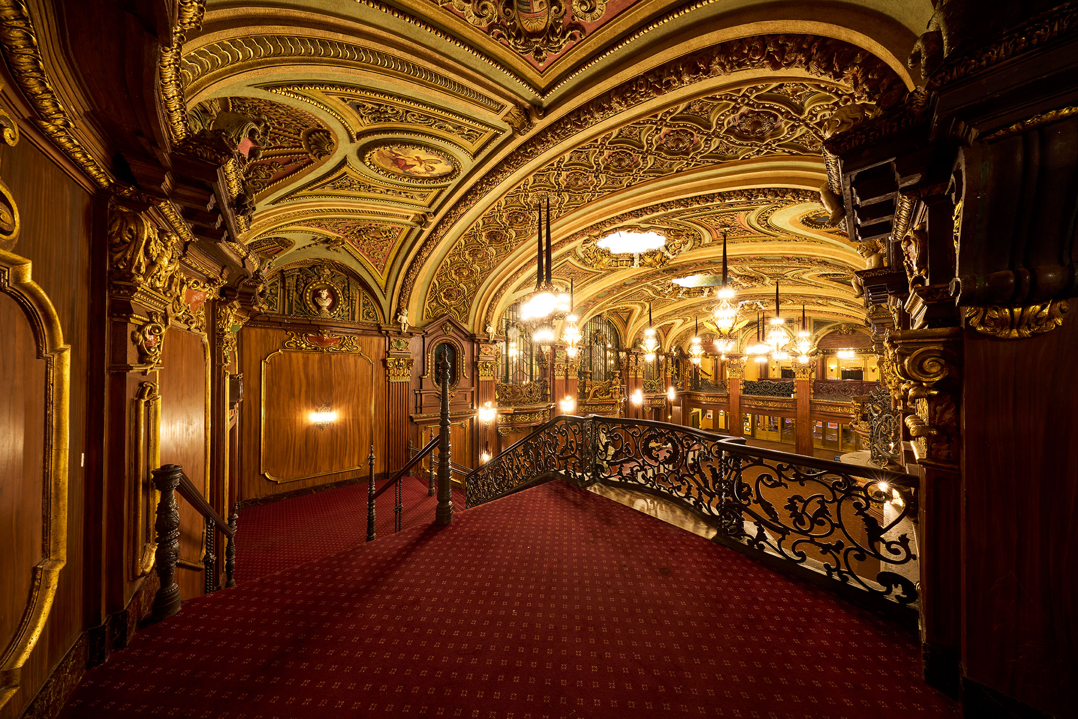 Red carpet and decorative railings overlook the illuminated lobby.
