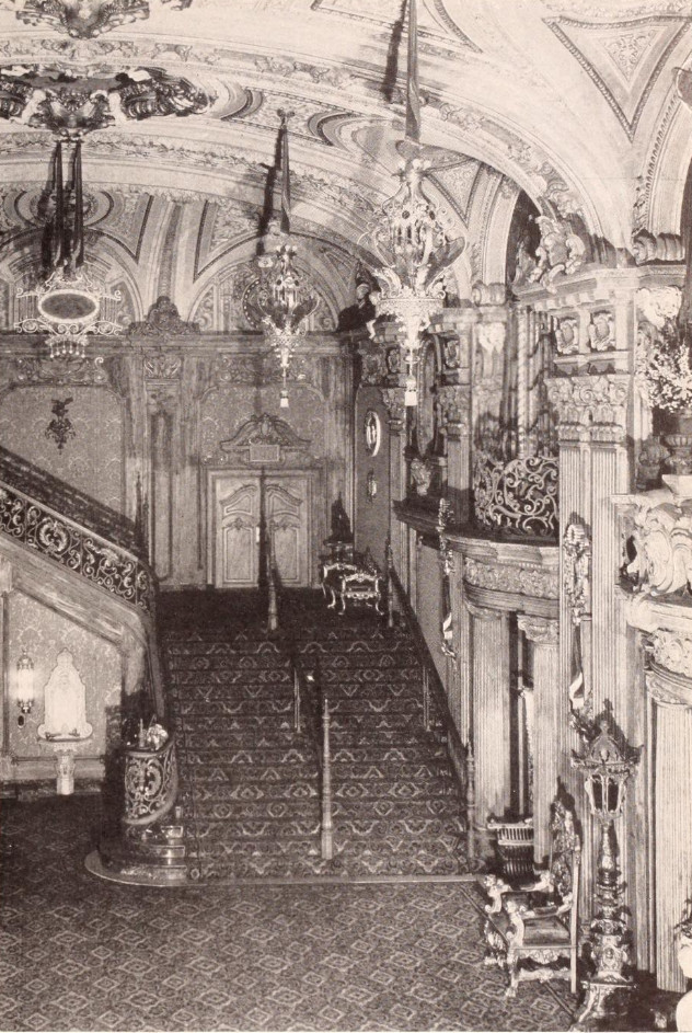 Early black-and-white photograph of the Paradise grand staircase, patterned carpet, and hanging chandeliers